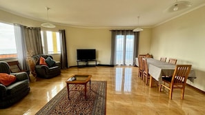 Un salon comprenant un canapé, une table basse, un téléviseur et un coin repas avec une table et des chaises.