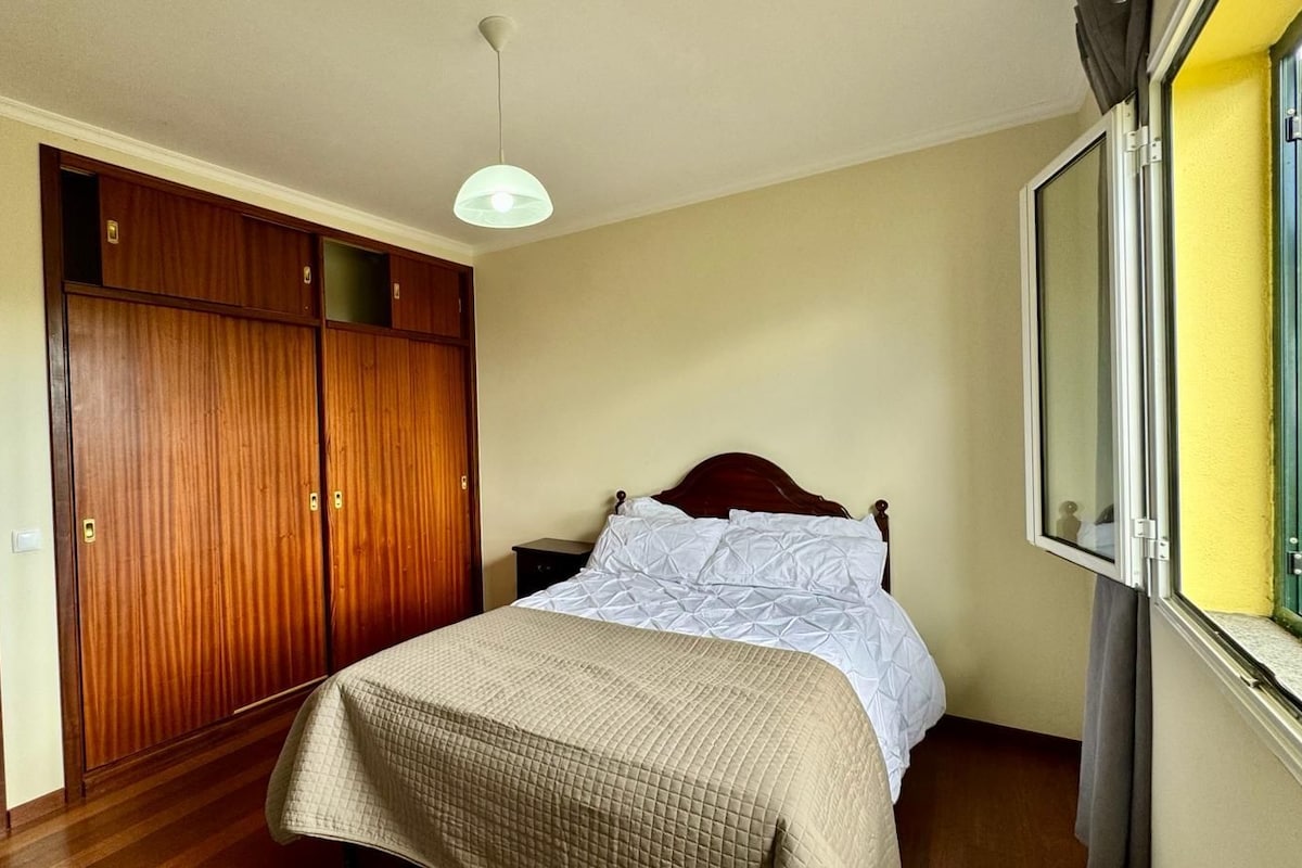 Une chambre à coucher avec un lit, une armoire en bois et une fenêtre.
