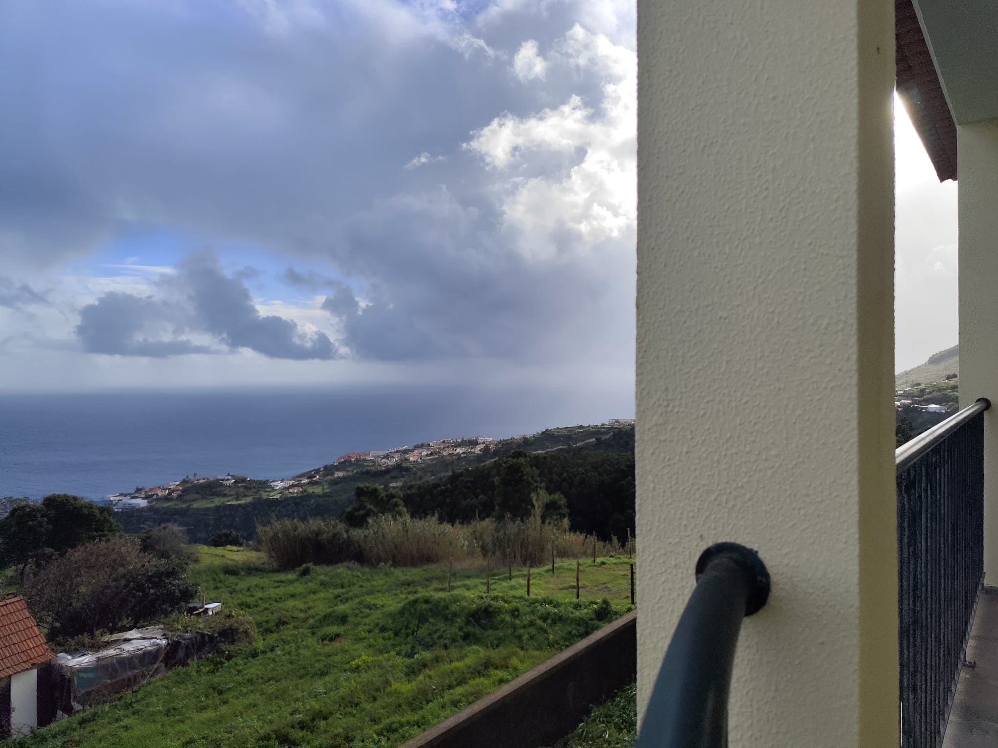 Un balcón con vista al mar y un paisaje montañoso.