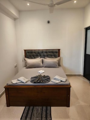 Een slaapkamer met een groot bed, een plafondventilator en een vloerbedekking.