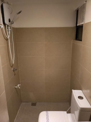 Een kleine, afgesloten douchecel met toilet en een handdoekhouder.