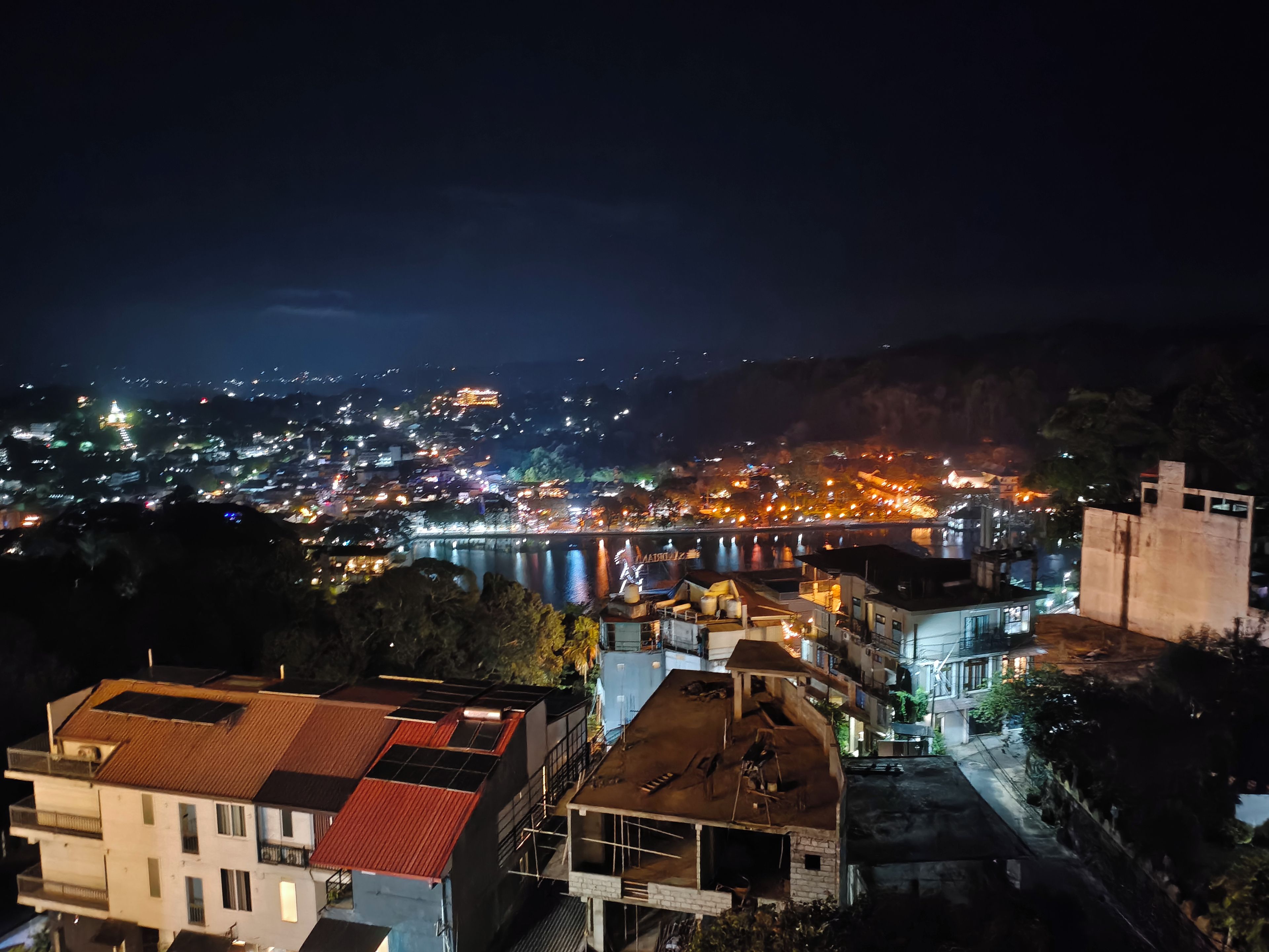 A nighttime view of a city with a river, buildings, and a bridge.
