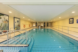 An indoor swimming pool with tiled walls, a lifeguard station, and a clear view of the pool area. - 2 Raum Appartement im IFA Fehmarn mit Balkon (Fehmarn)