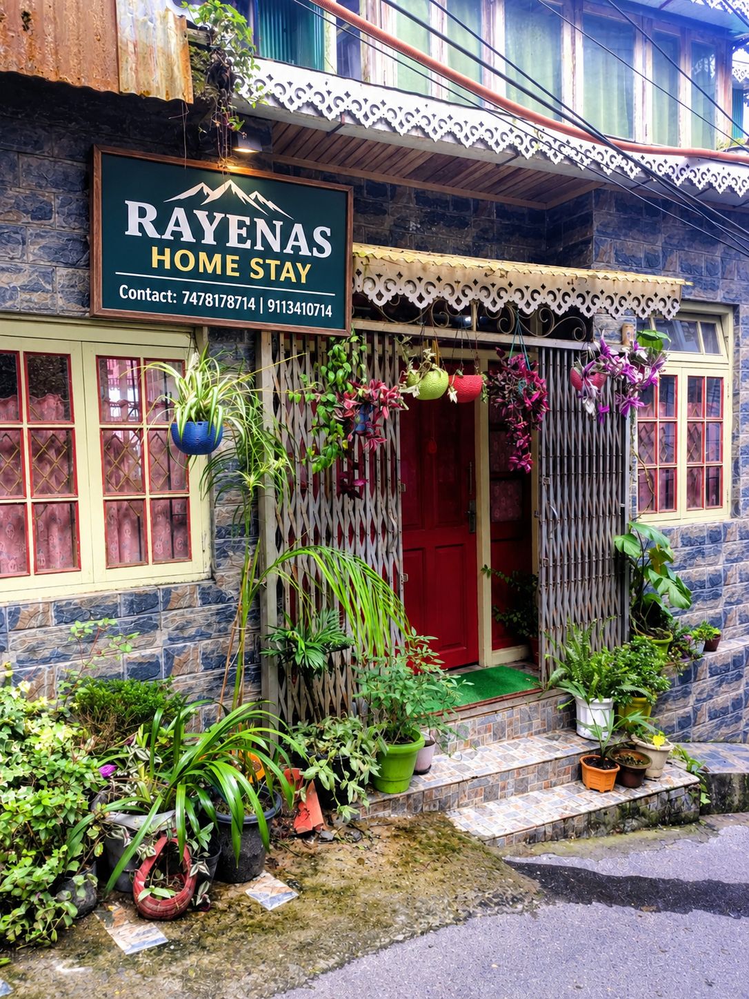 A house with a sign that reads 'RAYENAS HOME STAY' and contact numbers.