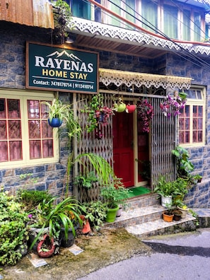 Une maison avec une enseigne indiquant « RAYENAS HOME STAY » et des numéros de téléphone à contacter.