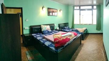 Una habitación con cama, dos mesitas de noche, una lámpara de pared y un ventanal con cortinas.