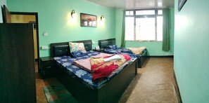 Une chambre avec un lit, deux tables de chevet, un luminaire fixé au mur et une fenêtre avec des rideaux.
