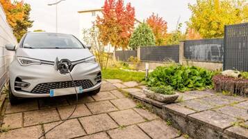 A silver car parked in a driveway with a charging station.
