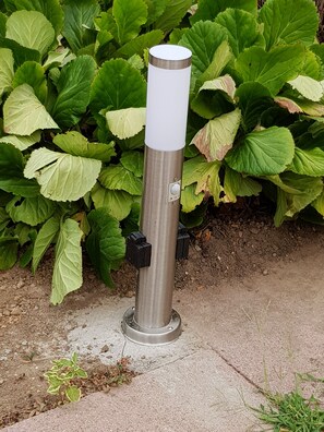 A metallic cylindrical object with a white top, possibly a water fountain, on a concrete surface with green foliage in the background. - Vrbo Property (Vandœuvre-lès-Nancy)