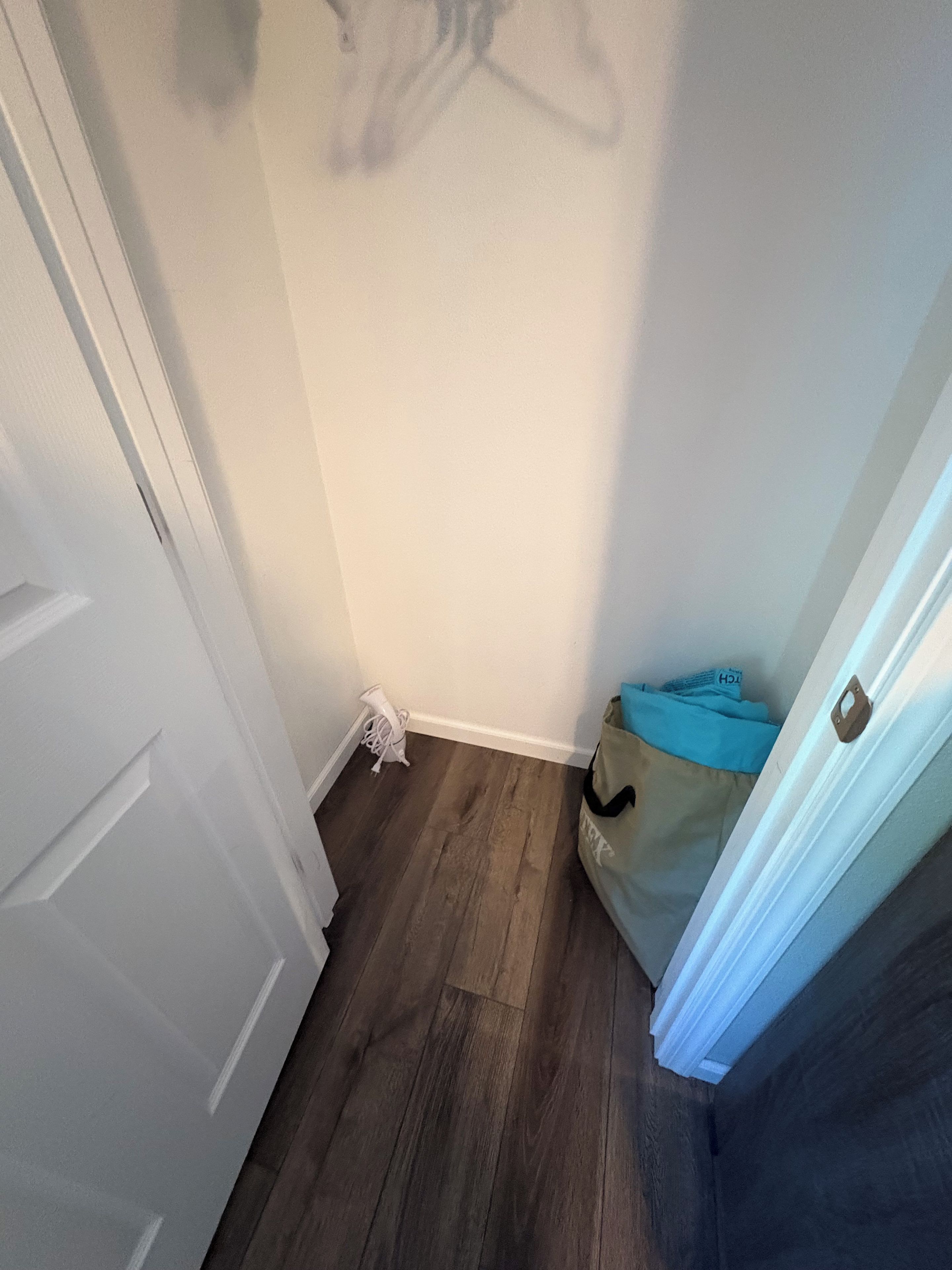 A hallway with a white door, a blue bag, and a white object on the floor.