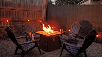 Feuerstelle mit vier Stühlen und einem Tisch, umgeben von Kies.