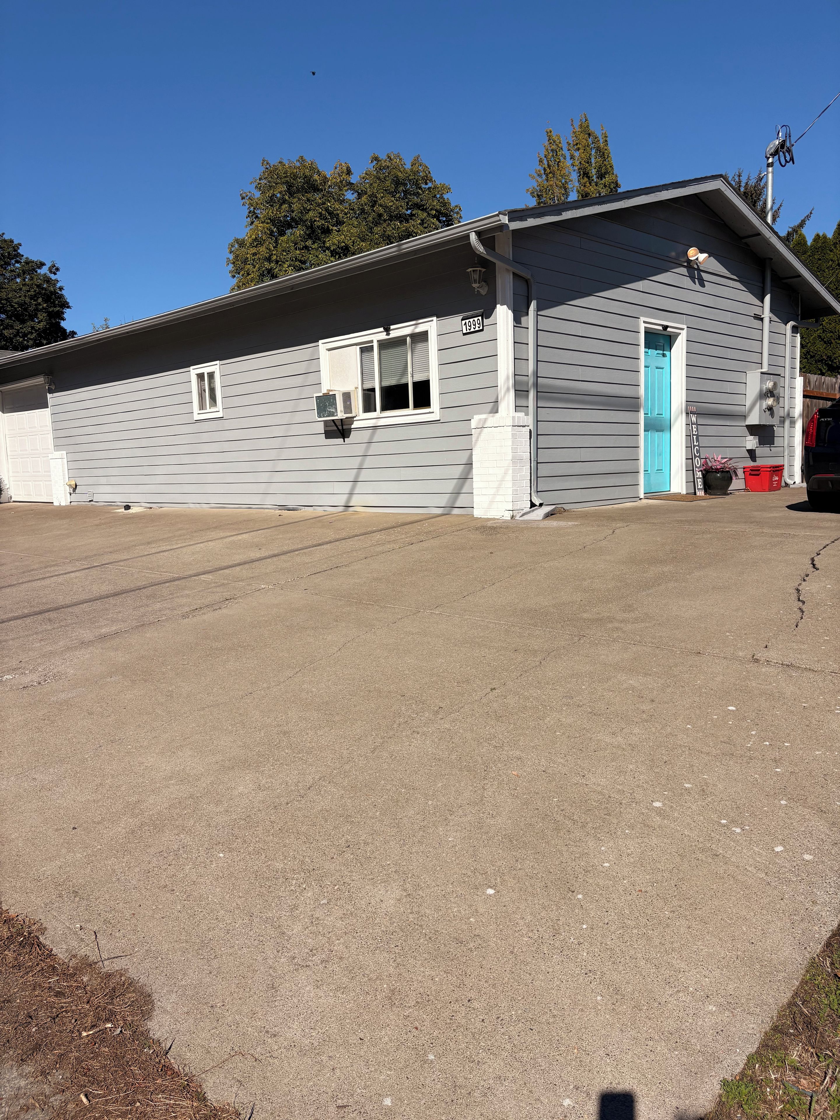 A single-story building with a garage door, a blue door, and a small window.