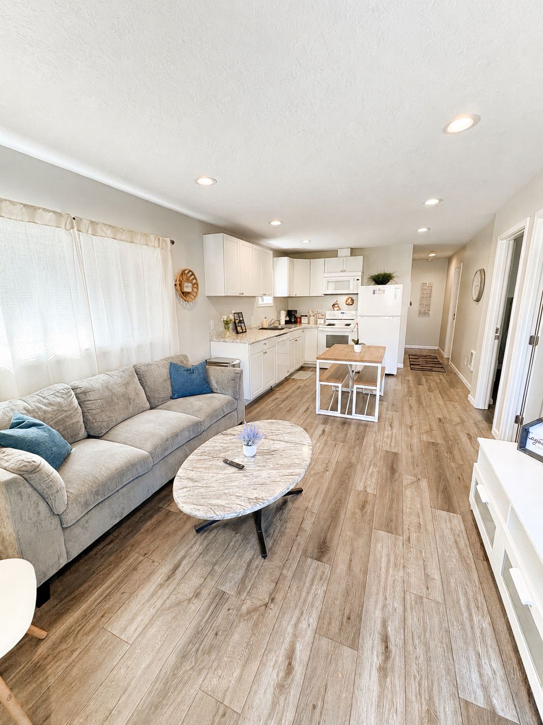 A modern living room with a sofa, coffee table, and a kitchen area in the background.