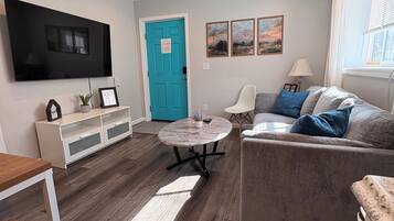 A modern living room with a flat-screen TV, a blue door, and a sofa with cushions.