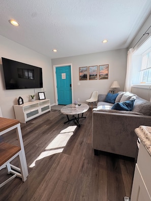 A modern living room with a flat-screen TV, a blue door, and a sofa with cushions. - 3-bedroom house in Keizer convenient located near I5 (Keizer)
