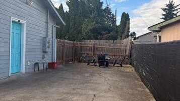 A residential backyard with a concrete patio, a wooden fence, and a blue door.