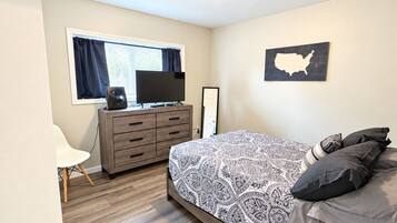 A bedroom with a bed, a dresser, a television, and a wall map.