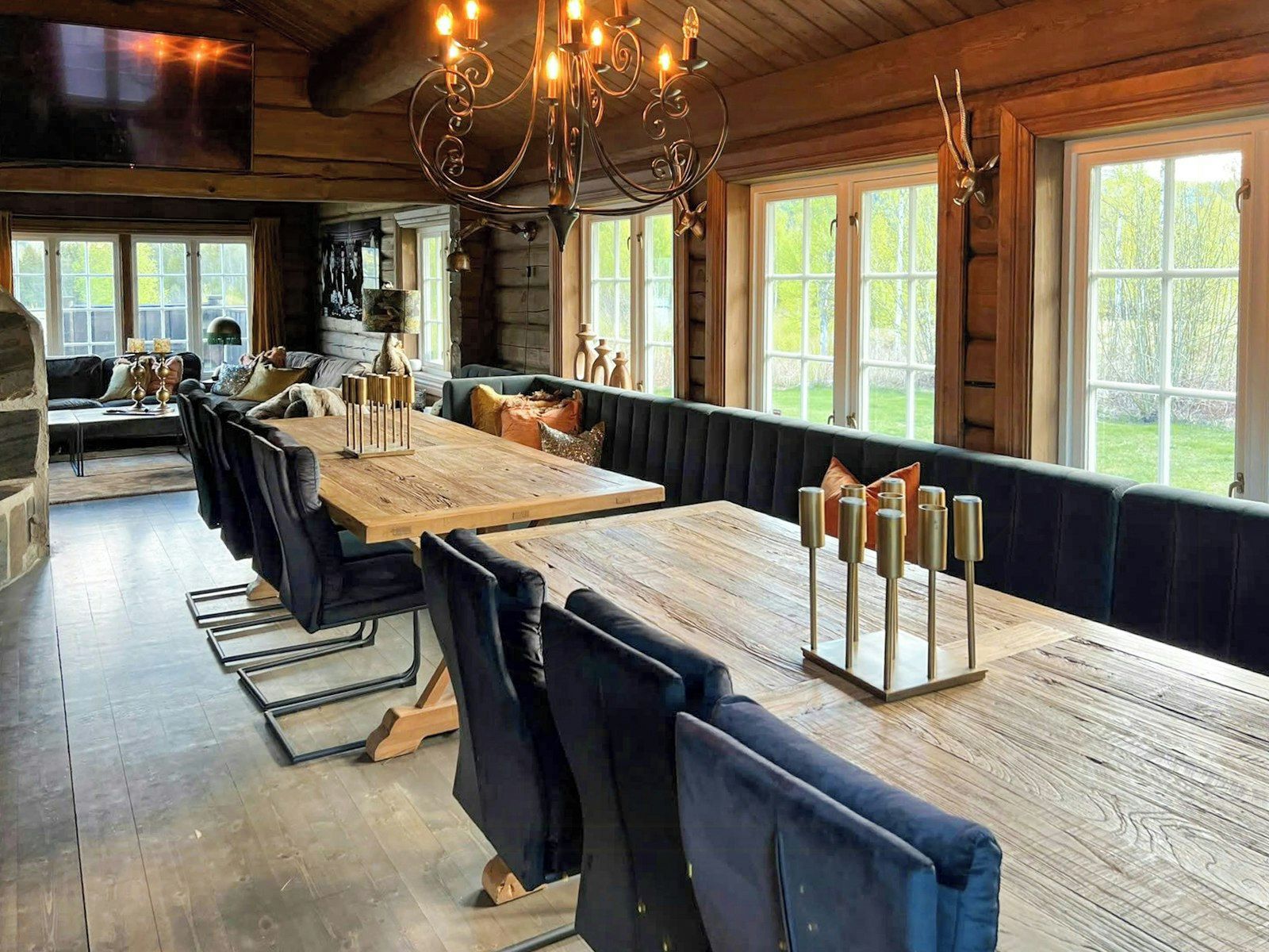 Un comedor amplio con una larga mesa de madera, bancos tapizados en negro y un candelabro.