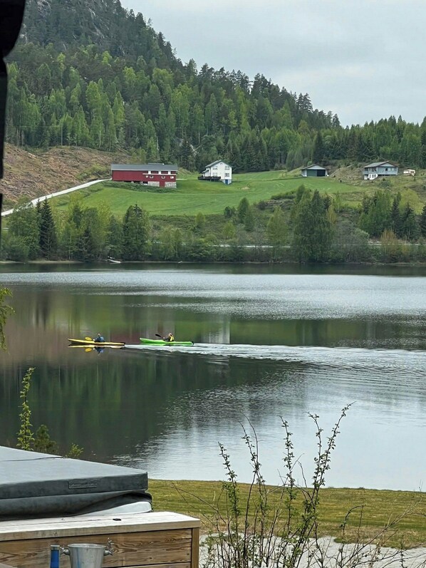A lake with a dock, a red barn, and a white house in the background.