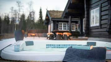 Un jacuzzi frente a una cabaña de madera con un libro titulado 'Jeffrey Archer'.