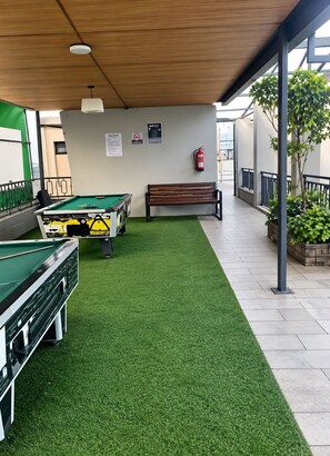 A pool table with a green felt surface, a wooden bench, and a fire extinguisher mounted on the wall. - Serene bed sitter apartment in the heart of Nairobi, private and cozy (Nairobi)