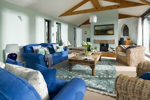 Ein Wohnzimmer mit blauem Sofagarnitur, einem Holztisch und Korbmöbeln.