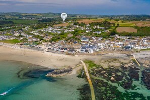 An aerial view of a coastal town with a beach, houses, and a rocky shoreline. - Little Acres - sleeps 12 guests  in 5 bedrooms (Marazion)