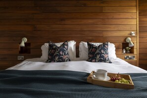 A neatly made bed with floral pillows, a bedside table with a lamp, and a tray with a cup and grapes. - Mowhay Barn - sleeps 6 guests  in 3 bedrooms (Helford)