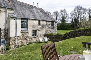 A stone house with a sloped roof, a small garden with a stone wall, and outdoor seating. - Mowhay Barn - sleeps 6 guests  in 3 bedrooms (Helford)