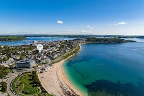 An aerial view of a coastal town with a beach, clear blue waters, and a mix of residential and commercial buildings. - Seashells Apartment - sleeps 2 guests  in 1 bedroom (Falmouth)