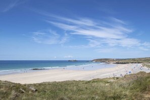 A beach with a clear sky, sandy shore, and a few people. - Skylark Beach House - sleeps 6 guests  in 3 bedrooms (Hayle)