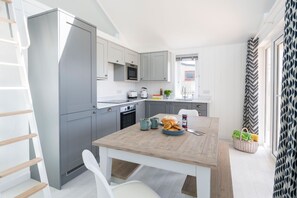 A modern kitchen with grey cabinets, a wooden table, and a built-in oven. - Skylark Beach House - sleeps 6 guests  in 3 bedrooms (Hayle)