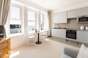 A modern kitchen with a dining area, large windows, and a view of the sea. - Starfish Studio Apartment - sleeps 2 guests  in 1 bedroom (Falmouth)