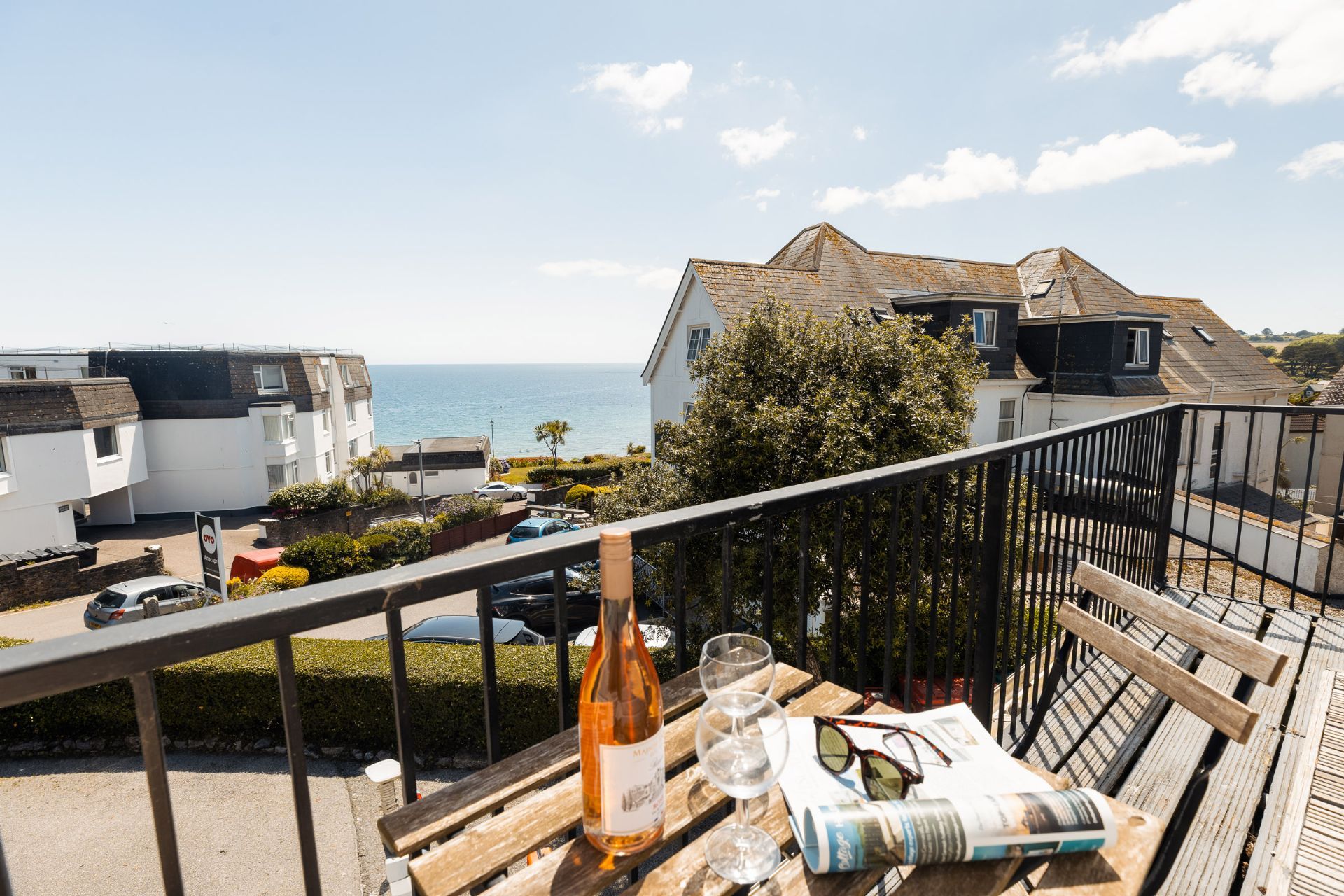 A balcony with a bottle, glasses, and a newspaper.