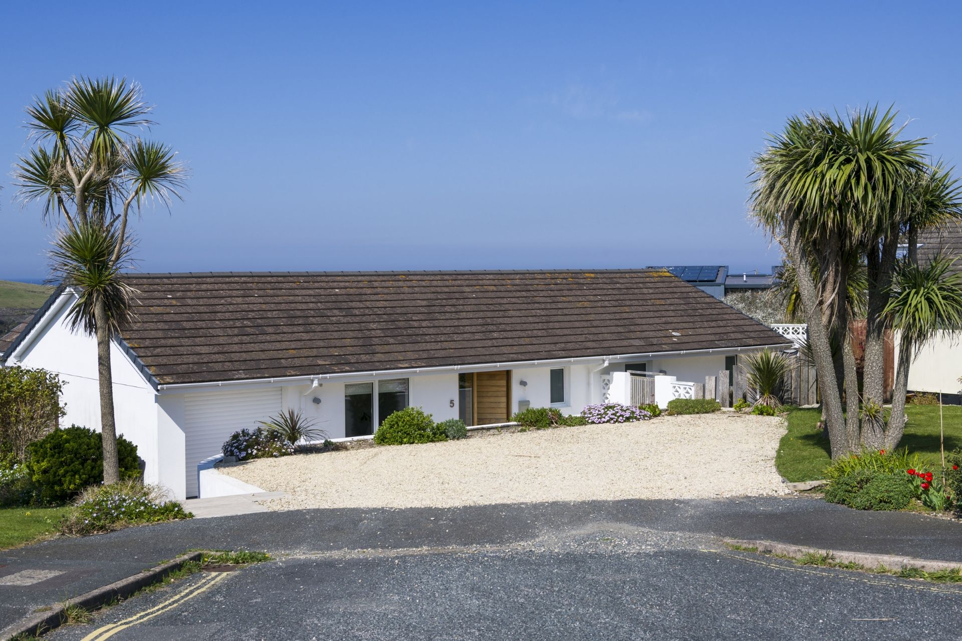 A single-story white building with a dark roof, a front door, and a small porch area.