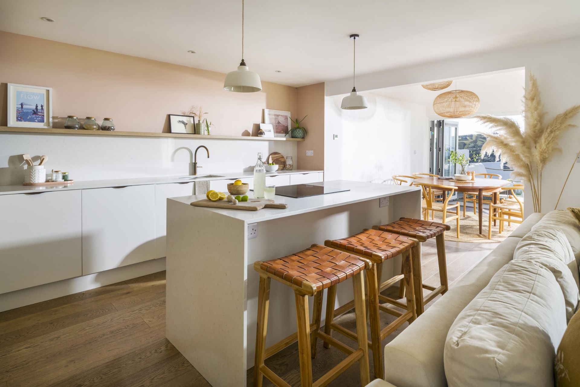 A modern kitchen with a central island, bar stools, and a dining area with a view.