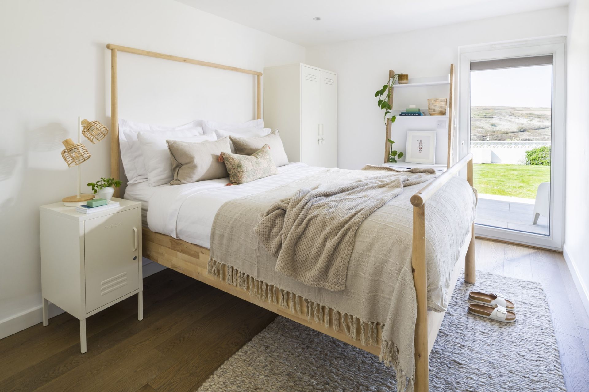 A bedroom with a bed, bedside table, and a view of the outdoors.