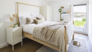 A bedroom with a bed, bedside table, and a view of the outdoors.