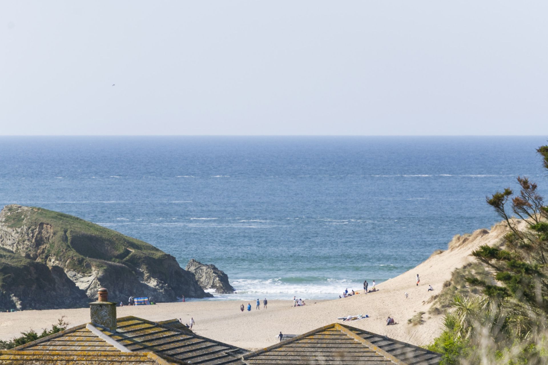 A coastal beach with a rocky cliff and a clear view of the sea.