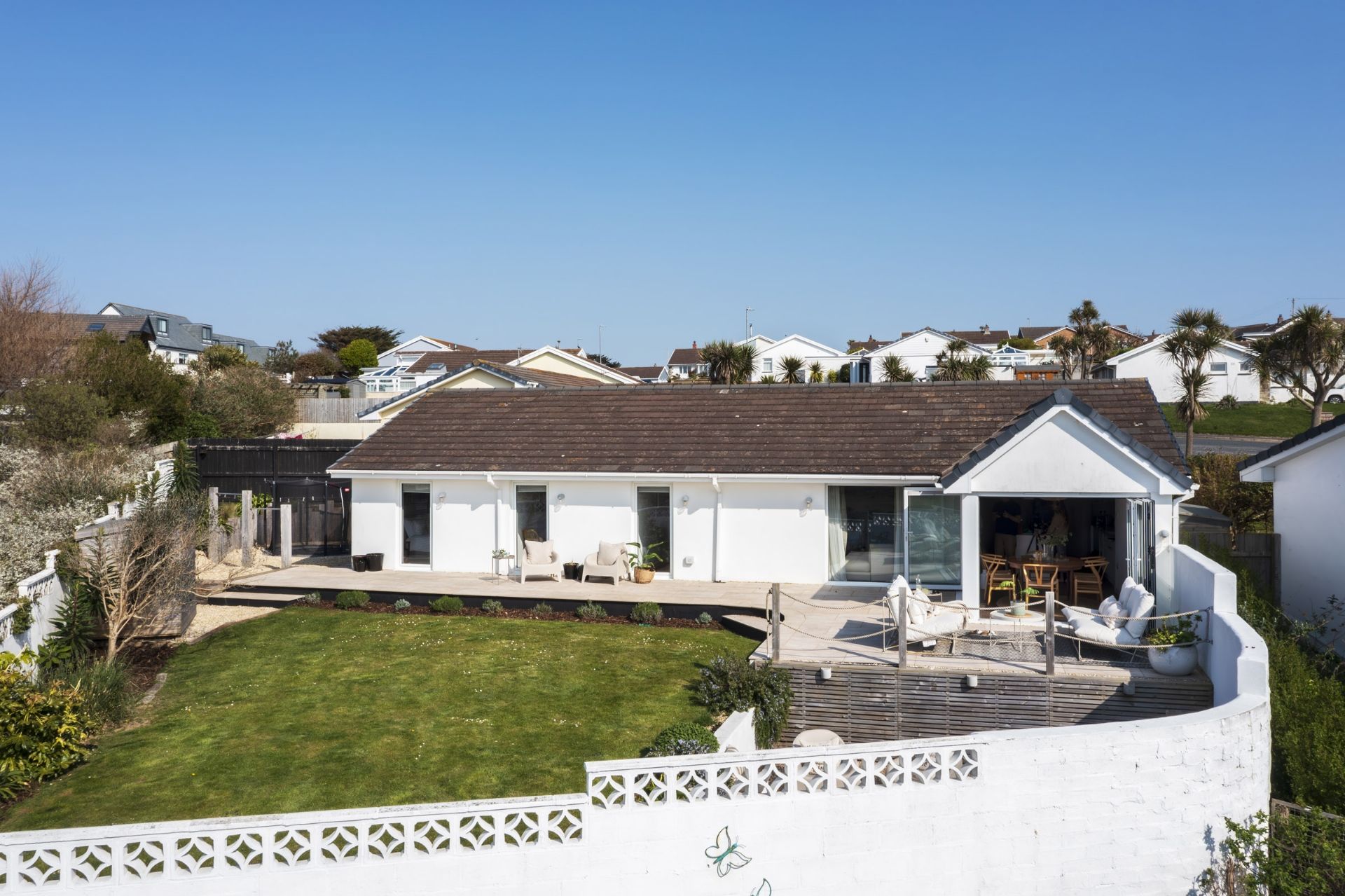 A two-story house with a flat roof, a covered patio, and a fenced yard.