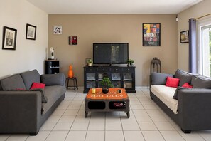 A living room with two grey sofas, a coffee table, a television, and a cabinet with glass doors. - House with a private pool - Sleeps 6 (Châteauneuf-de-Gadagne)