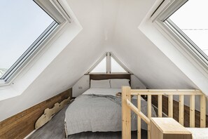 A small, triangular attic bedroom with a wooden bed and a view through the skylight. - Seamist  - sleeps 2 guests  in 1 bedroom (Hayle)
