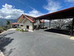 Une maison avec un toit rouge, une véranda et une vue sur les montagnes.