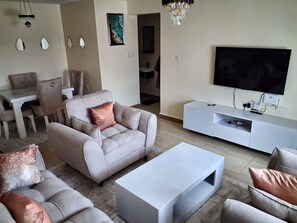 Un salon comprenant un canapé, une table basse, un téléviseur et un coin repas avec des chaises et une table.
