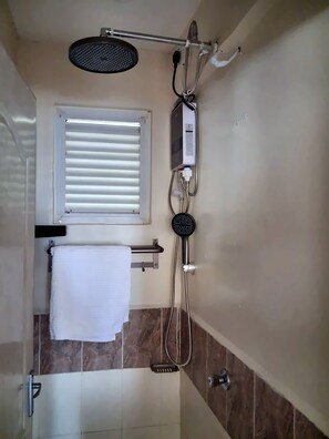 A bathroom with a shower, a towel rack, and a window with blinds. - King Serenity Suite
_Fabulous 1 bedroom apartment_ (Ongata Rongai)