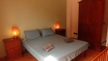 Una camera da letto con un letto, due comodini, un'armadio in legno e un pavimento piastrellato.