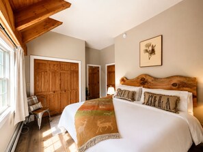Un dormitorio con una cama grande, un armario de madera y vistas a un pasillo.