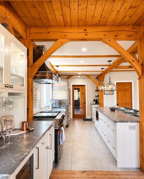 Una cocina con vigas de madera, armarios blancos y una isla central.