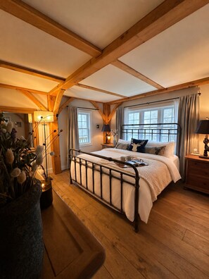 Une chambre à coucher avec un plafond en bois, un lit avec un cadre en métal, une table de chevet et une fenêtre avec des rideaux.