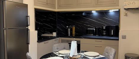 A modern kitchen with a built-in oven, a dining table set for four, and pendant lighting.